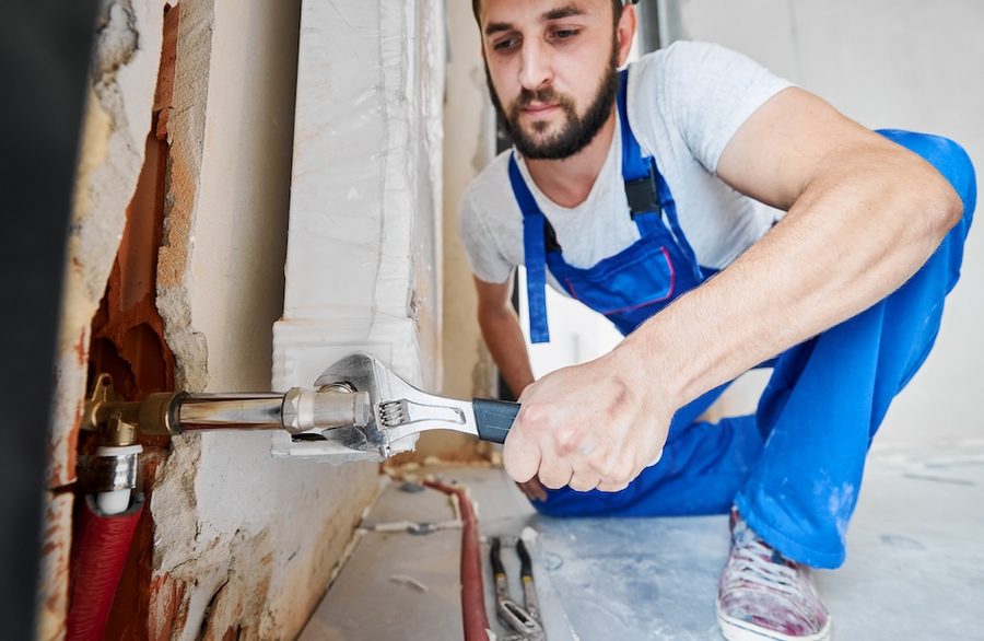 Plumber repairing a leaking pipe under a sink in a Karachi home